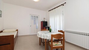 A small, tidy room with a bed, a dining table with chairs, a radiator, and a door. - Amazing apartment in Zadar with WiFi (Zadar)