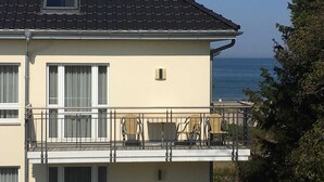Un immeuble de deux étages doté d’un balcon, d’une petite fenêtre et offrant une vue sur la mer.