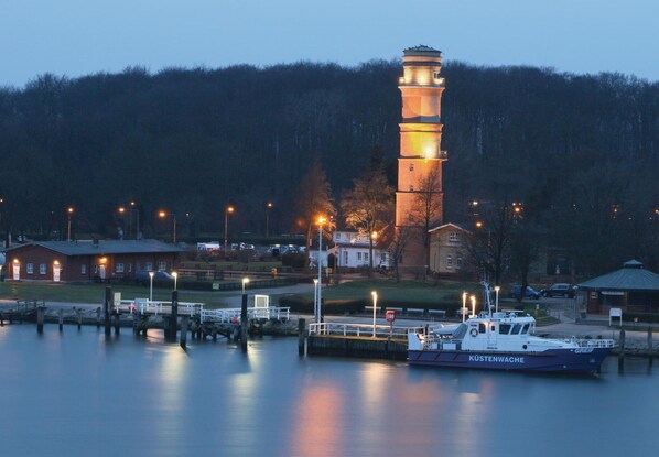 Een vuurtoren in de schemering met een boot die ernaast ligt.