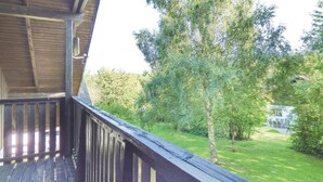 A wooden deck with a view of a grassy yard and trees. - Ferienhaus 18 in Thalfang (Thalfang)