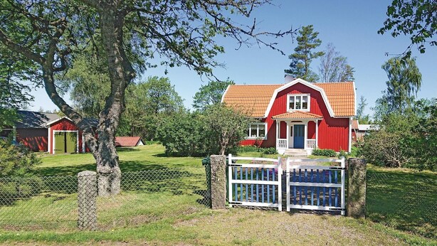 Ett rött hus med en vit veranda och en blå grind framför.