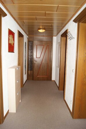 A hallway with wooden doors, a white cabinet, and a patterned wall.