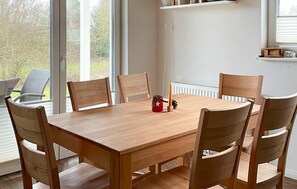 Una mesa de madera para comer con seis sillas, una vela y un pequeño objeto decorativo encima.