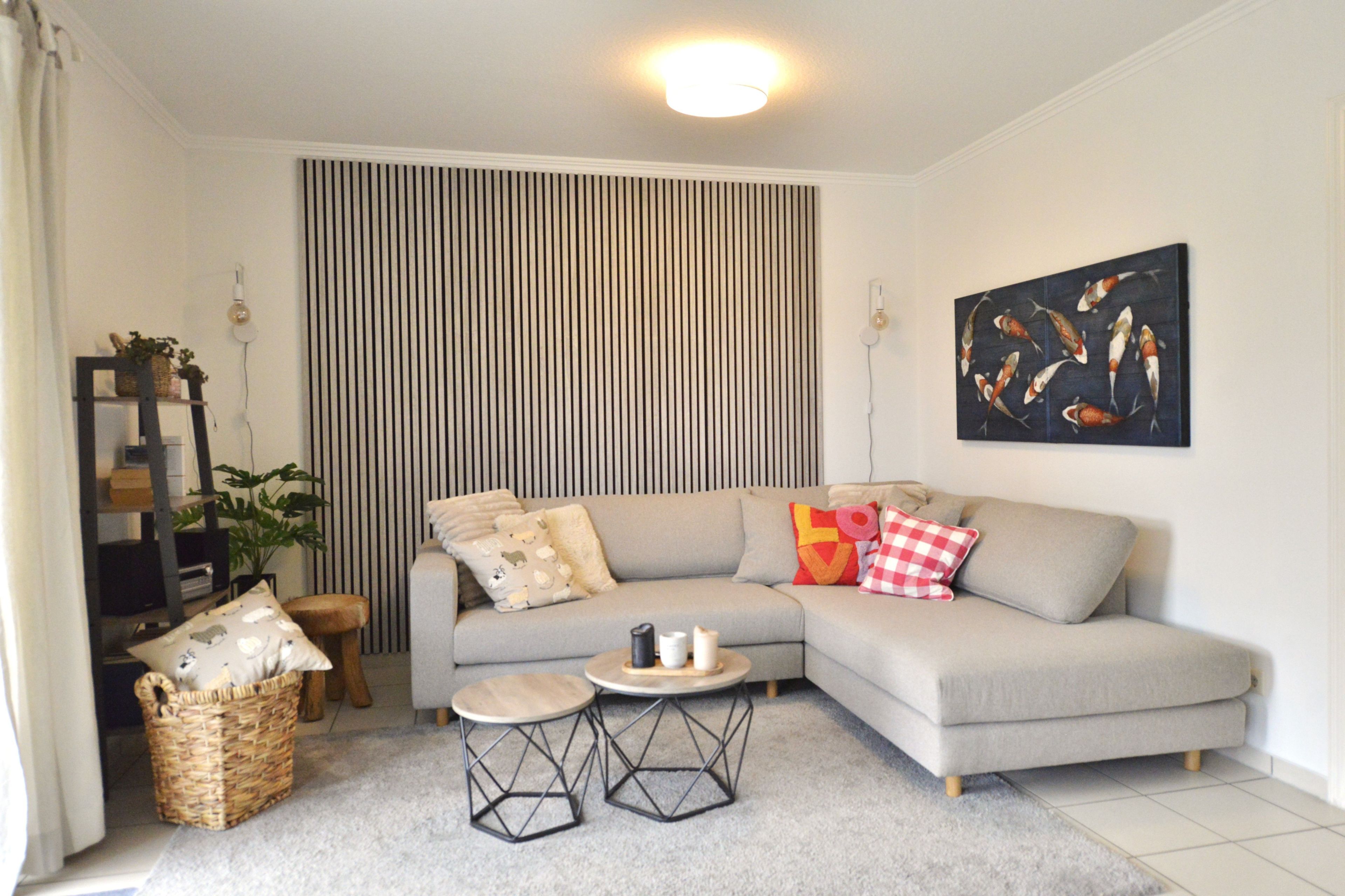 Una sala de estar con un sofá modular, una mesita redonda, una cesta de mimbre y una obra de arte colgada en la pared.