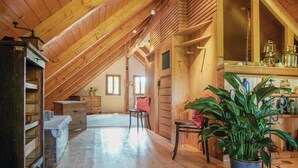 A spacious attic room with wooden beams, a large potted plant, and a rustic wooden cabinet. - schönes Ferienhaus Reinersdorf (Reinersdorf)