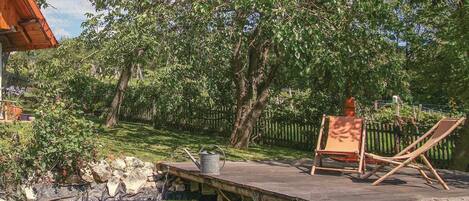 A garden with a pond, wooden deck, and two lounge chairs.