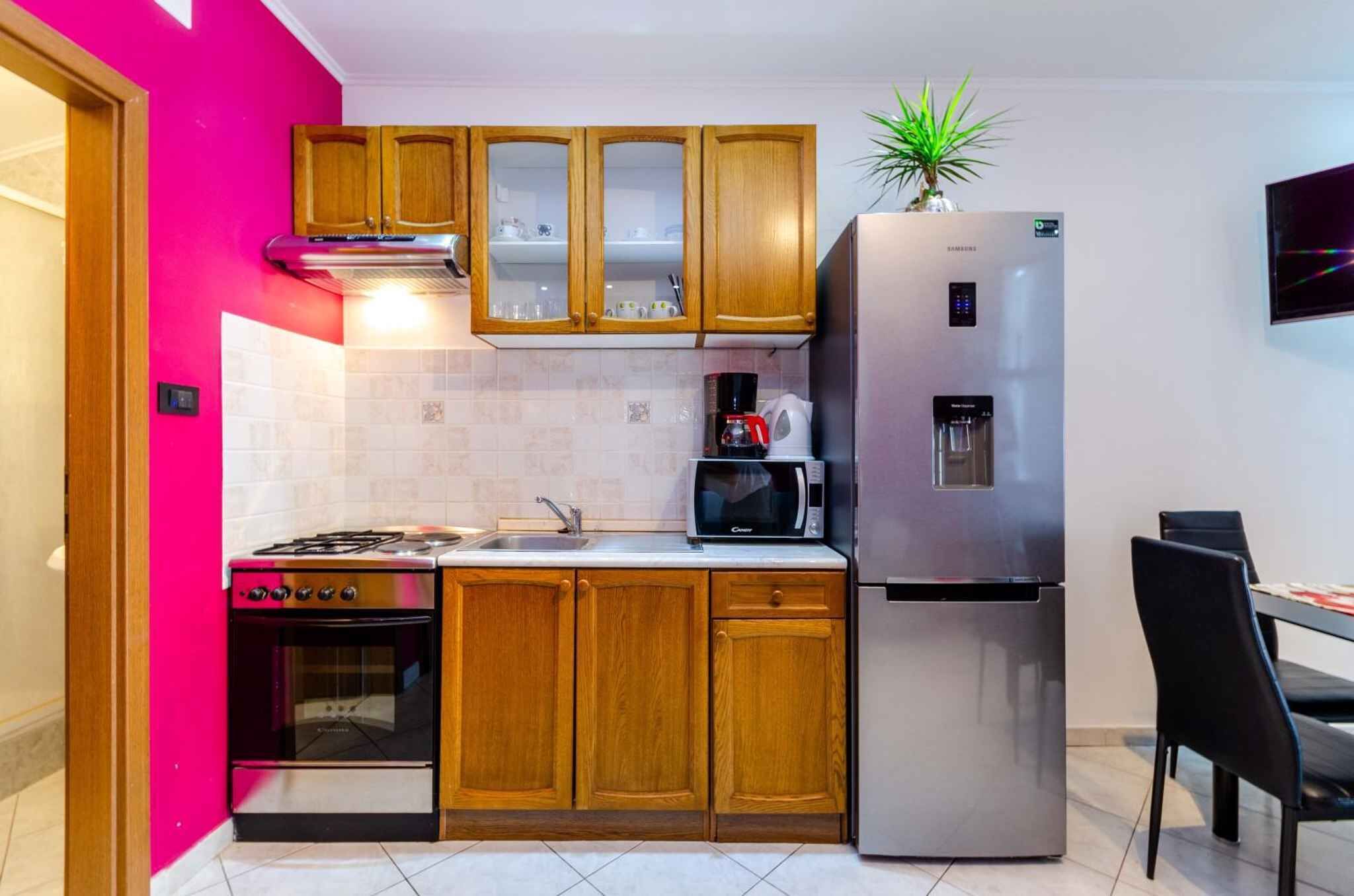 A compact kitchen with wooden cabinets, a stainless steel refrigerator, a microwave, and a gas stove.