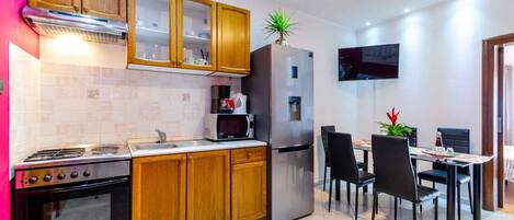 A modern kitchen with wooden cabinets, a stainless steel stove, a microwave, and a refrigerator.