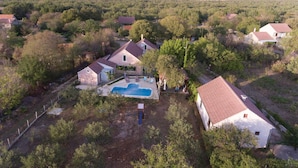 Vista aérea de um bairro residencial com casas, piscina e vegetação ao redor.