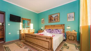 Quarto com cama de madeira, penteadeira, televisão e decoração na parede.