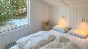 Un dormitorio con una cama, una ventana y una estantería en la pared.