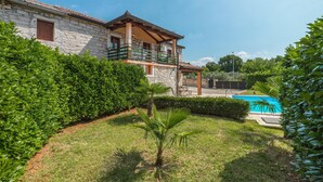 Une maison en pierre dotée d’un balcon, d’une piscine et d’un jardin bien entretenu.