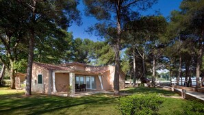 A single-story house with a tiled roof, a patio with outdoor furniture, and a view of a lake. - Villa with pool for 6 people (Umag)