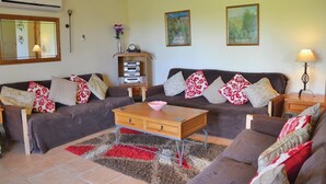 Una sala de estar con un juego de sofá, una mesa de centro, una estantería y dos cuadros en la pared.