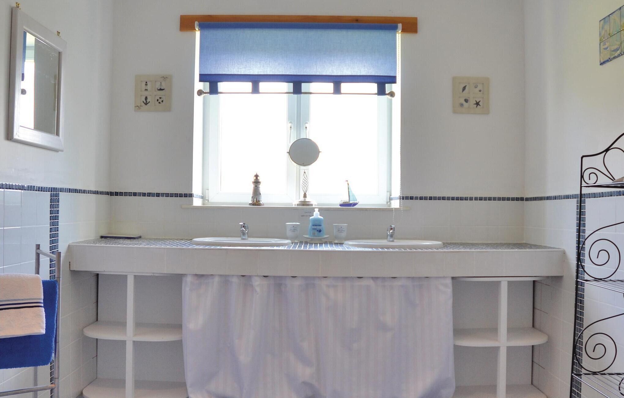 A bathroom with a large window, a sink, and a mirror.