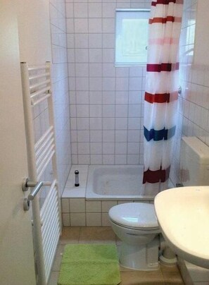 Une petite salle de bain avec des toilettes, un lavabo et une baignoire.