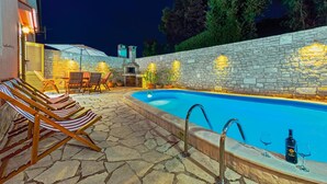An outdoor swimming pool with stone walls and a stone floor, surrounded by lounge chairs and a barbecue area. - Beautiful home in Banjole (Banjole)