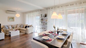 A modern living room with a sofa, coffee table, and dining area set up for a meal. - Beautiful home in Banjole (Banjole)