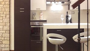 A modern kitchen with dark cabinets, a white countertop, and two bar stools. - Beautiful home in Banjole (Banjole)