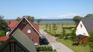 Ett bostadsområde med hus, en asfalterad uppfart och en vattenyta i bakgrunden.