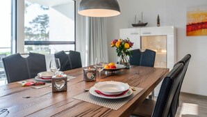 Una mesa de comedor dispuesta con platos, vasos y una vela, con vistas al exterior a través de una ventana.