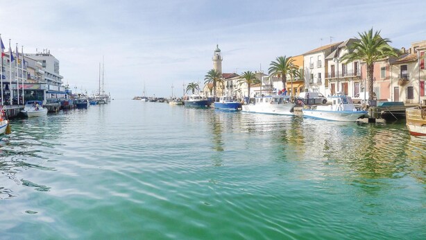 A canal with boats docked on both sides, a prominent tower in the distance, and buildings lining the canal. - Beautiful home in Aigues-Mortes with WiFi (Aigues-Mortes)