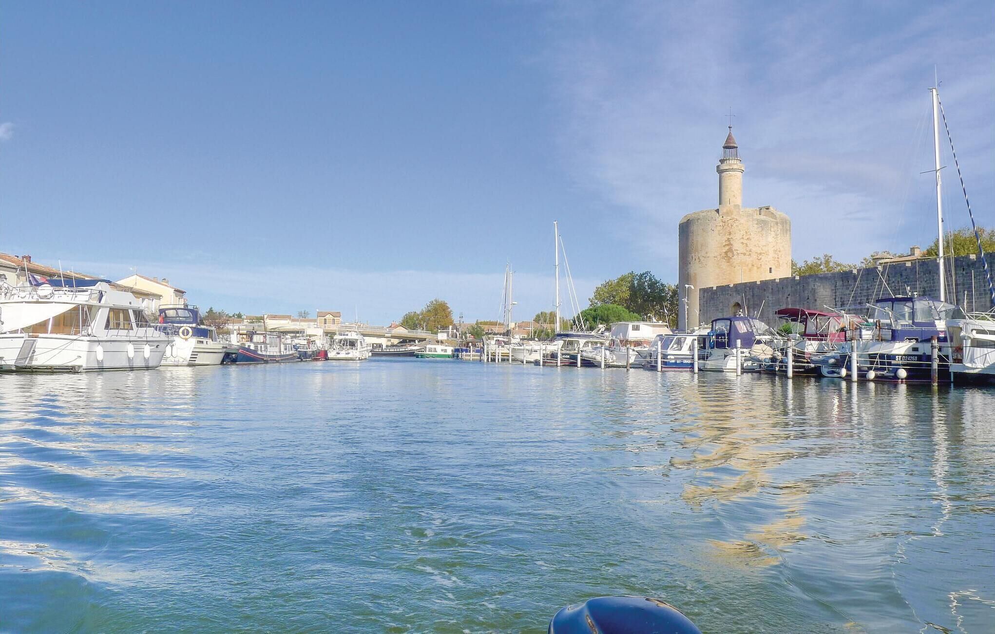 Ein Hafen mit vertäuten Booten, einem markanten Turm und blauem Himmel.