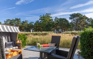 Een terras met een tafel en stoelen, omringd door groen en bomen.