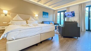 A hotel room with a large bed, a sofa, a TV, and a view of the outdoors. - Awesome apartment in Binz with outdoor swimming pool (Prora/Rügen)