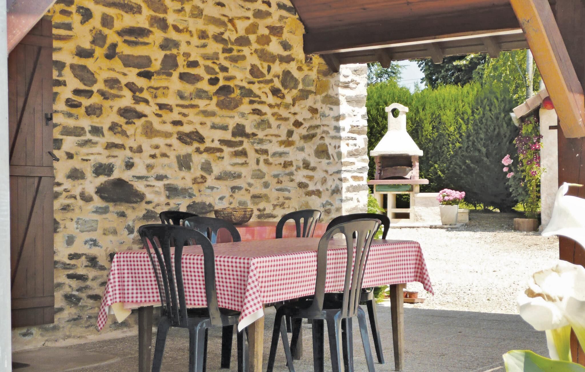 Eine Außenpatio mit Steinmauern, einem Tisch mit kariertem Tuch und Stühlen.