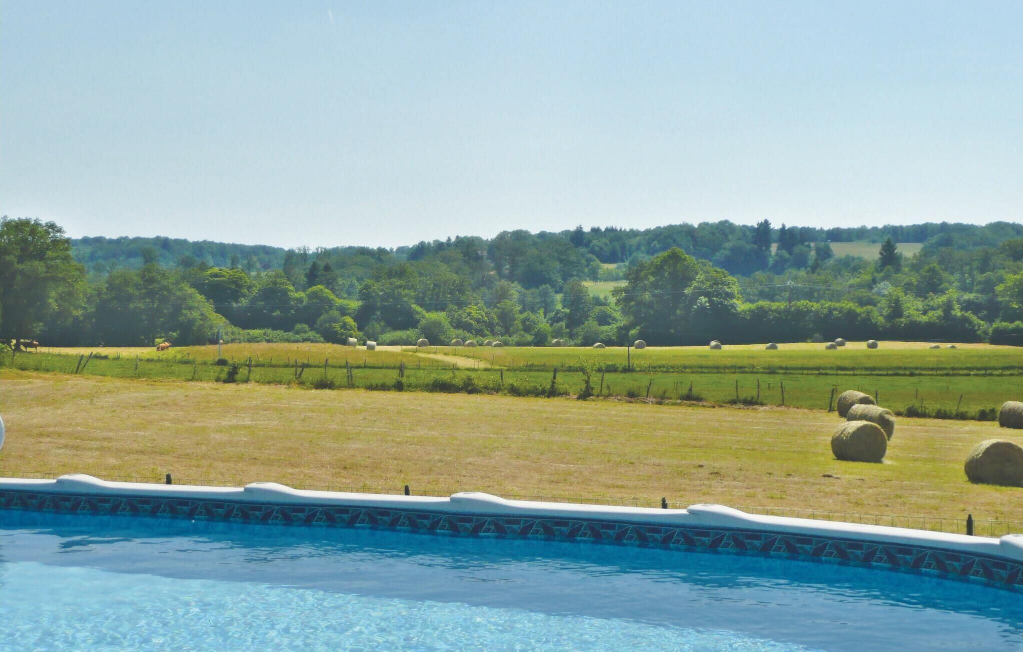 Una piscina con vistas a un campo cubierto de césped y pacas de heno.