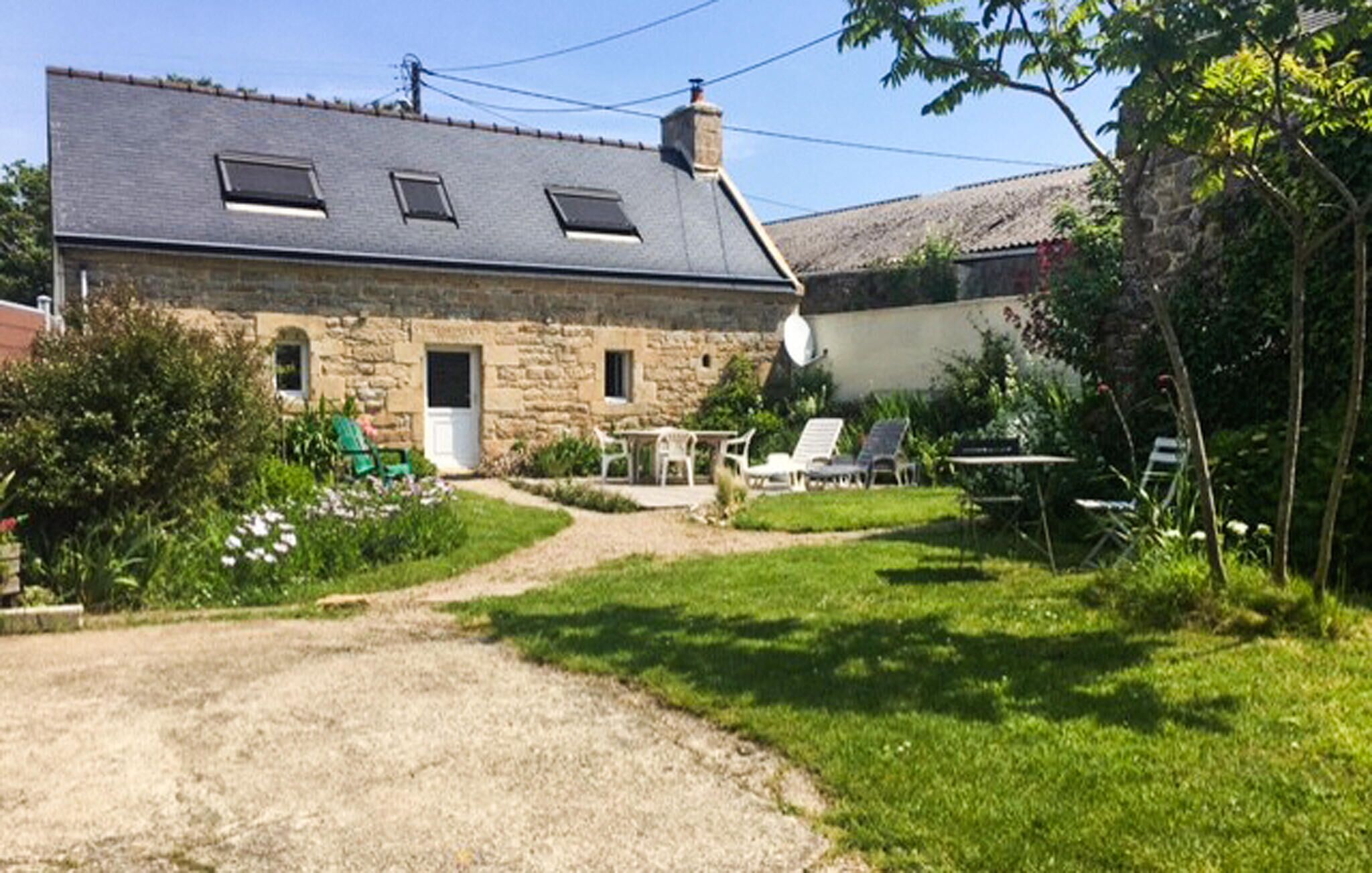 Una casa in pietra con vialetto sterrato, giardino con piante verdi e mobili da esterno.