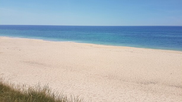 Ein weiter Sandstrand mit einem klaren, blauen Meer.