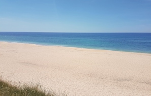 Ein weiter Sandstrand mit einem klaren, blauen Meer.