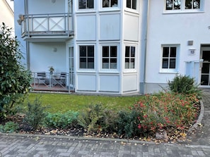 Ein zweistöckiges Gebäude mit Balkon und kleiner Außenlounge.