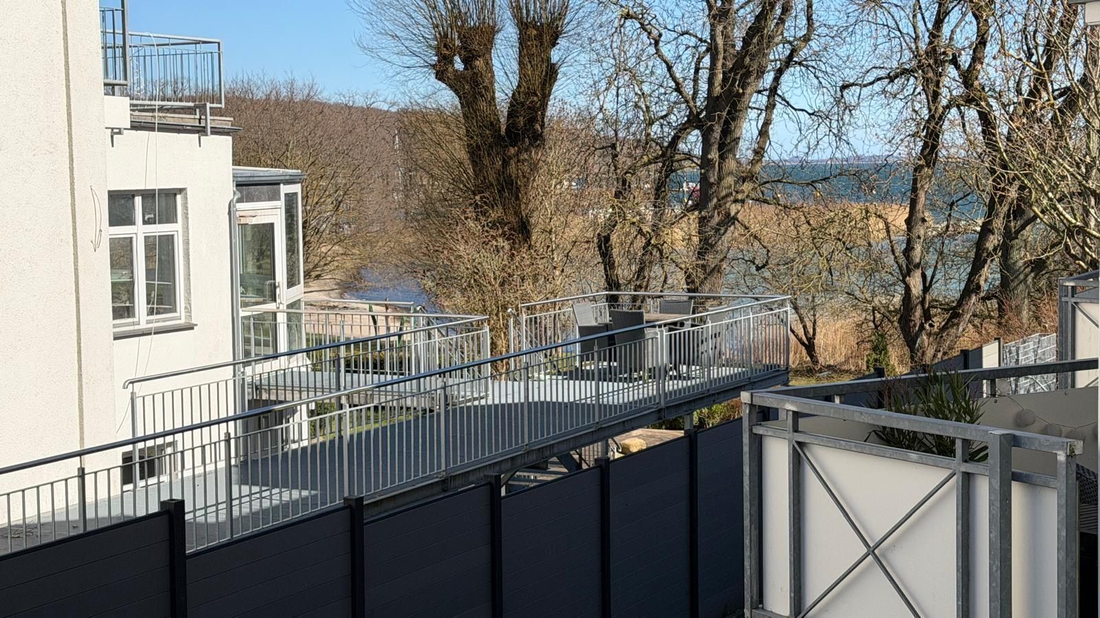A modern building with a covered outdoor area, including a metal bridge and seating.
