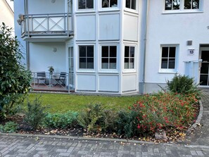 Un edificio a due piani con un balcone e un piccolo spazio esterno con posti a sedere.