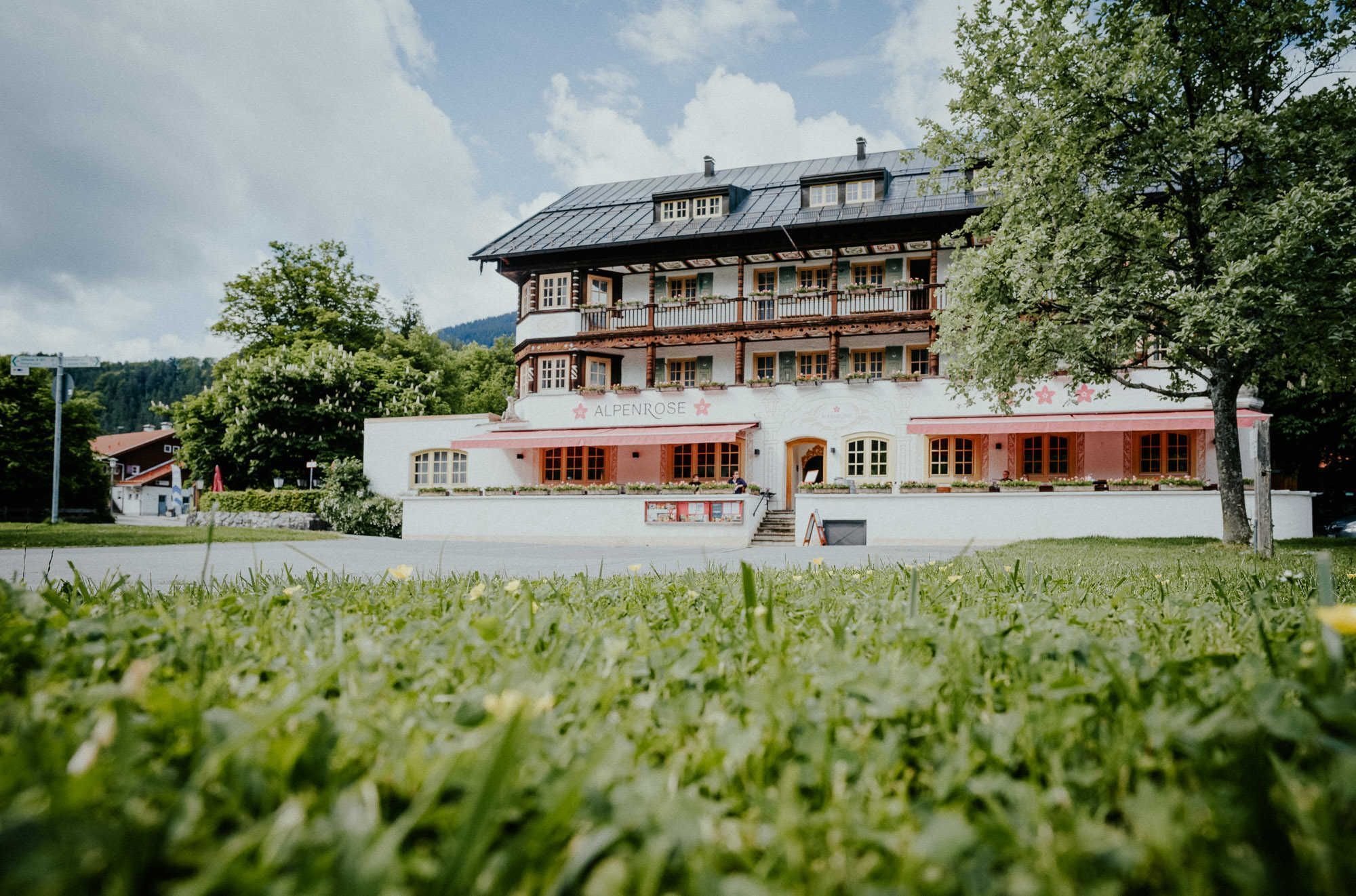 En traditionel bygning med balkon, et skilt der viser 'ALPENROSE' og et belagt indgangsparti.