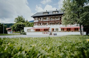 Een klassiek pand met balkon, een bord waarop 'ALPENROSE' staat, en een verhard entreegebied.