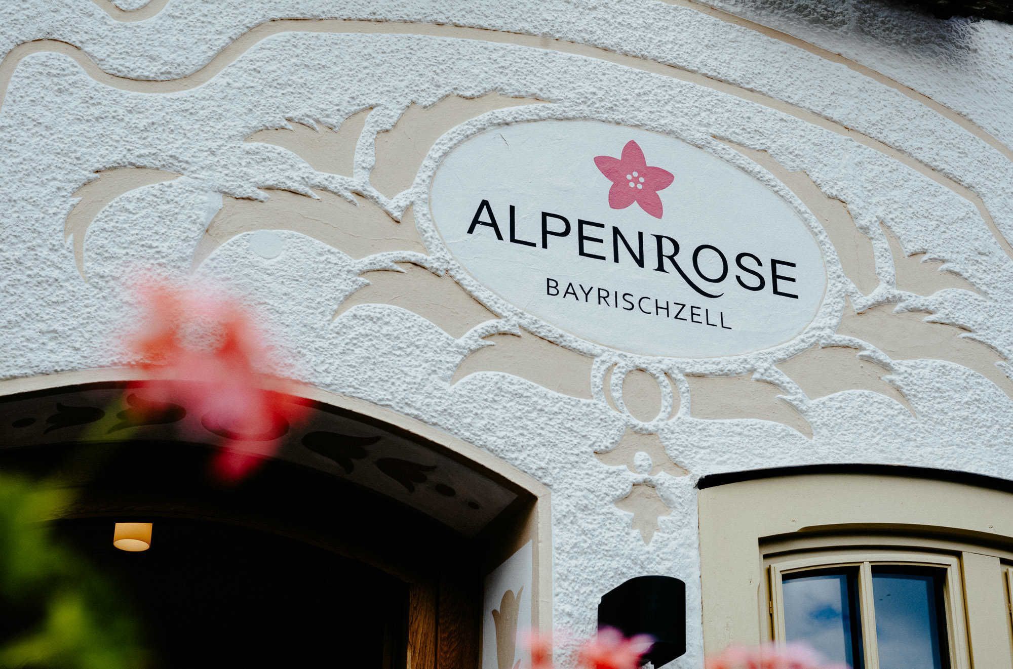 La façade d’un immeuble porte une enseigne sur laquelle on peut lire : « ALPENROSE BAYRISCHZELL ».