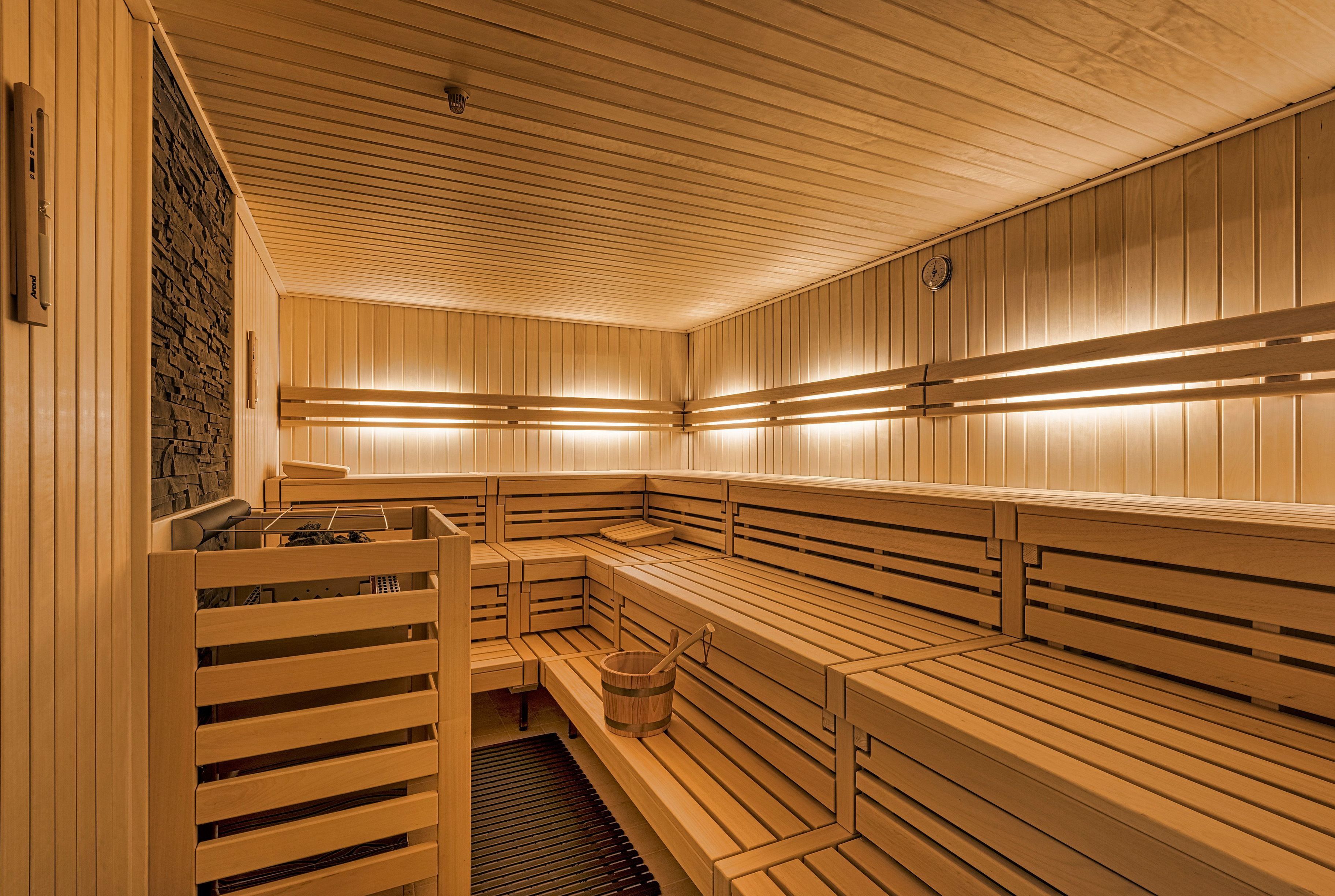 Una sauna con bancos de madera, una pared de piedra y una puerta de madera.