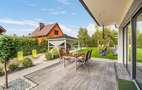 A patio with a table and chairs, a hanging chair, and a covered seating area. - Gorgeous home in Nowecin with WiFi (Nowecin)