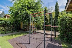 An outdoor gym area with exercise equipment, surrounded by greenery and a building in the background. - Holiday apartment only 250 m from the sandy beach on the Gold Coast (Siófok)