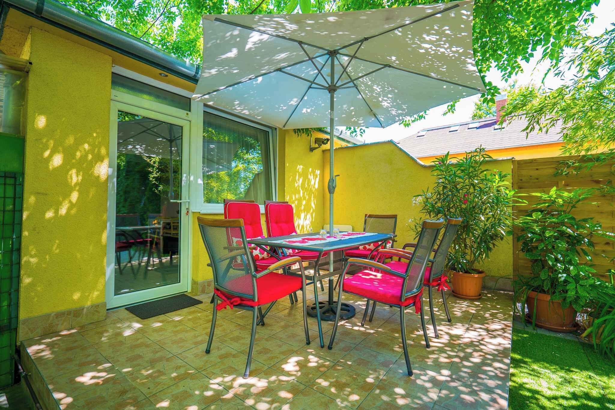 An outdoor patio with a table and chairs, a large umbrella, and potted plants.