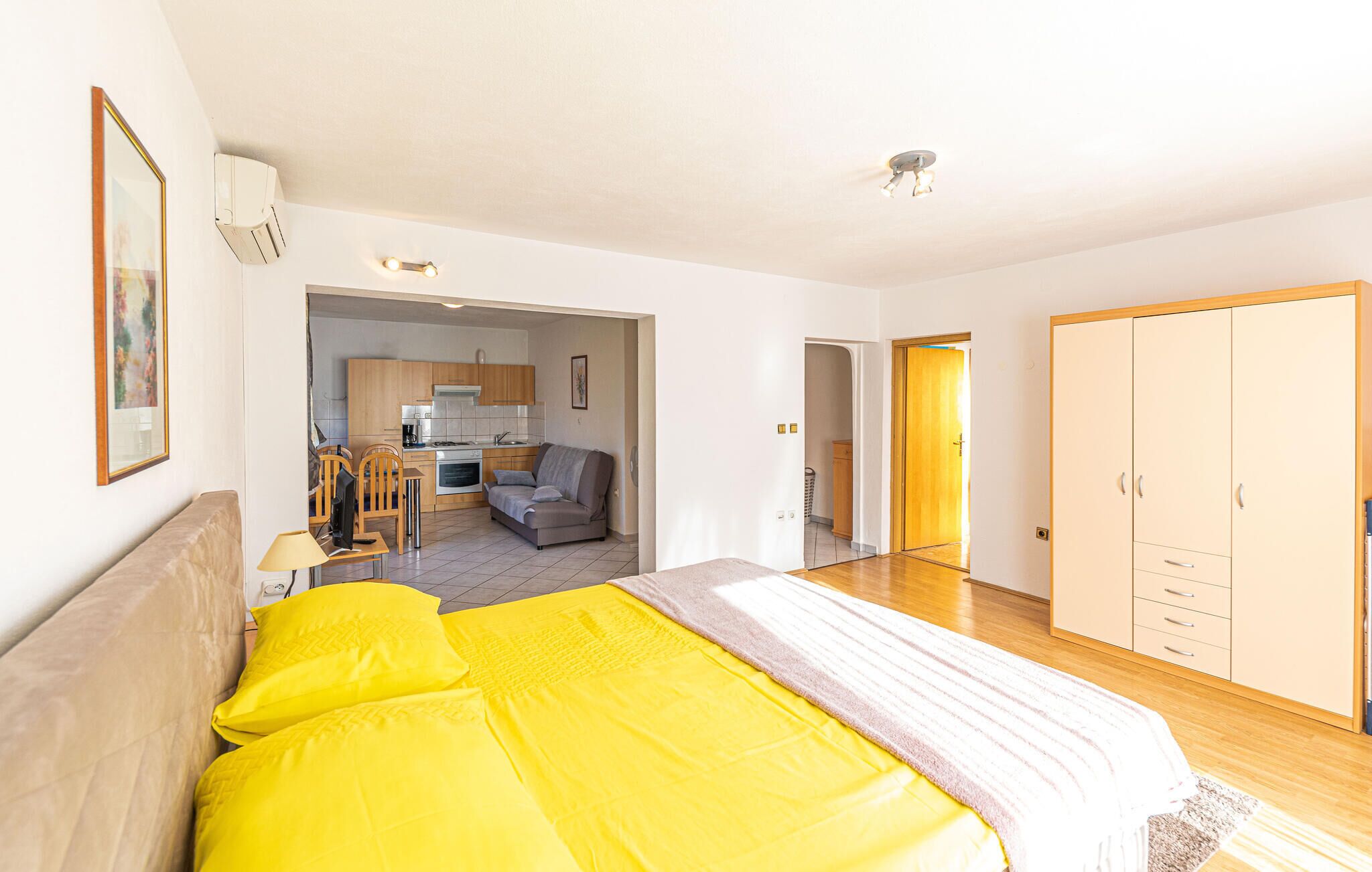 Ein Schlafzimmer mit einem großen Bett, einer Küchenzeile, einer Wohnbereich mit einer Couch und einem Kleiderschrank.