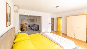 Een slaapkamer met een groot bed, een kitchenette, een zithoek met een bank en een kledingkast.