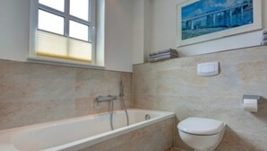 Ein Badezimmer mit Badewanne, Toilette und Fenster.