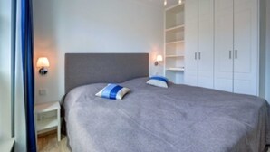 Ein Schlafzimmer mit einem großen Bett, Nachttischlampen, einem Kleiderschrank und einer Deckenleuchte.