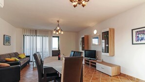 Una sala de estar moderna con sofá, sillas, una mesa de comedor y televisor.