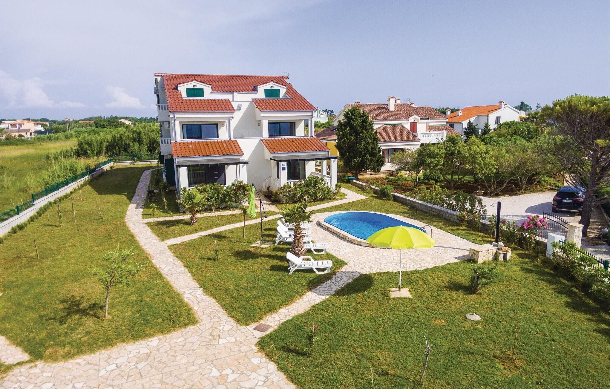 Een moderne villa met een zwembad, omgeven door een verzorgd gazon en een kiezelpad.